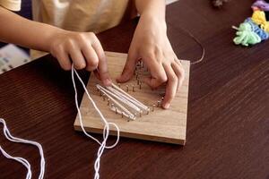 Little hands weave string around nails, crafting a beautiful design. A mix of patience, learning, and fun photo