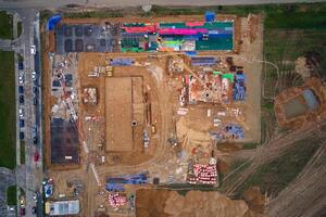 Aerial view of construction site with cranes, foundations and building materials. Residential building under construction. Progress of new development in small town photo