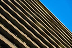 Contemporary architectural design with repeating geometric balconies against clear blue sky. Symmetry and minimalistic in modern urban building photo