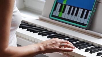 Hands playing a keyboard while following an interactive learning app on a tablet. Technology enables self-education in music without traditional lessons. video