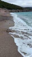 A stormy sea with crashing blue waves under dark clouds at the beach in Lustica Bay Montenegro. The powerful ocean swells and dramatic sky create a breathtaking display of natures force. video