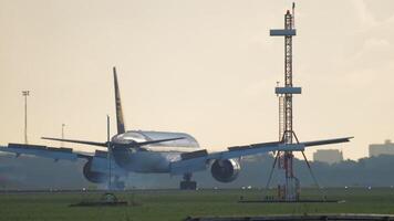 A commercial airplane slows down after landing on a brightly lit runway, completing its arrival video