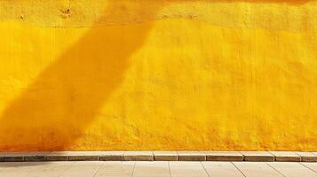 Bright yellow wall with a shadow casting down from above on the top left corner. A stone sidewalk is located at the bottom. photo
