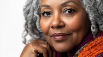 Portrait of an older woman with gray curly hair. Smiling softly while looking at the camera, with natural lighting. photo