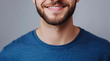 Close-up of a smiling man with a beard wearing a blue shirt, showcasing a friendly and approachable demeanor. Focus on positive expression. photo