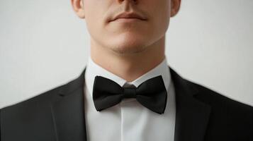 Close-up portrait of a person wearing a black tuxedo, bow tie, and white shirt against a neutral background. Classic formal attire. photo