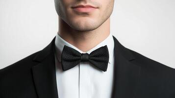 Formally dressed man with a neat bow tie, showcasing an elegant shirt and a sharp suit jacket against a neutral backdrop, ready for a gala photo