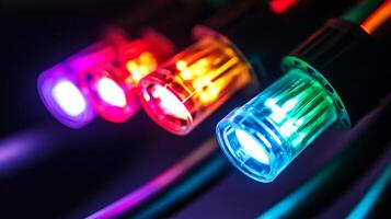 Close-up of illuminated optical fibers showcasing vibrant colors like purple, red, orange, and green against a blurred background. photo