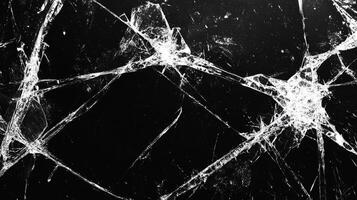 A stark black background is dramatically fractured with a network of sharp, white cracks, creating a compelling, abstract texture. photo