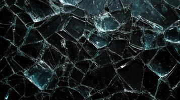 Shattered surface of clear, textured material displaying numerous sharp fractures and reflective qualities against a dark background. photo