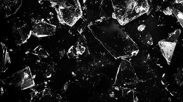 Shattered glass pieces scattered across a dark surface, creating a stark contrast and a visually striking pattern. photo