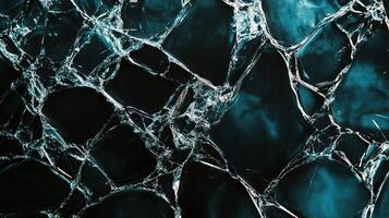 An abstract textured background with broken glass effect, showing a dark teal and black color palette with intricate cracks running through. photo