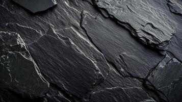 Textured surface of dark rock layers, creating a rugged, natural abstract pattern with highlights accentuating the sharp edges and ridges. photo