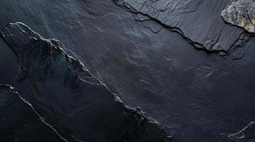 Dark stone surface shows textured layers, subtle shifts in tone. A somber elegance emanates from the stark, fragmented composition. photo