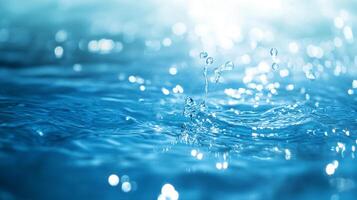 Water surface illuminated by sunlight, small drops forming a delicate splash in a serene, clear blue environment. photo
