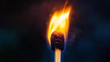 Illuminating the dark with a single flame, the match burns bright. The darkness surrounds it, a symbol of warmth and light. photo