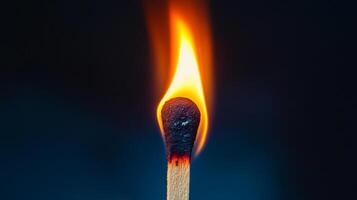 A close-up shot of a wooden matchstick with a bright orange flame against a dark background, highlighting the detail and intensity of the fire. photo