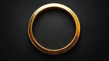 Golden circular ring on a black textured backdrop. The ring's aged texture contrasts with the smooth surface enhancing visual interest. photo
