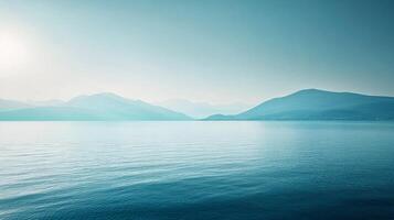 A serene water view showcasing muted tones of blue and green mountains reflecting in the calm water, creating a soothing and tranquil atmosphere. photo