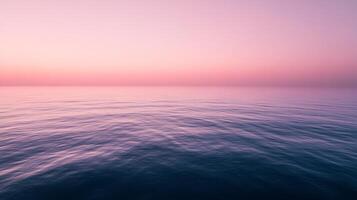 A serene pink sunset casts a tranquil reflection on calm ocean waters, inviting the viewer to immerse themselves in the beauty of nature and peaceful moments. photo
