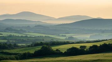 A tranquil landscape featuring rolling green hills and distant mountains shrouded in a soft, hazy light. Natural beauty and peaceful scenery. photo