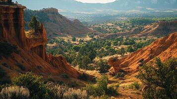 Scenic canyon vista with red rock formations, lush greenery, and distant mountains under a hazy sky, highlighting the beauty of nature. photo