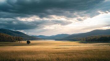 Golden field under a moody sky. Sunlight breaks through storm clouds over serene valley, creating tranquil and dramatic landscape. photo