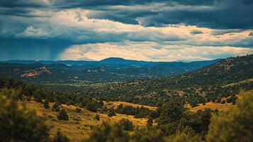 Scenic vista of layered hills and distant mountains under a dramatic sky with rain falling in the distance offering a sense of vastness. photo