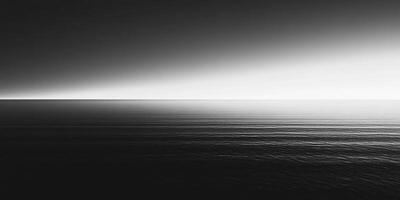 Black and white seascape featuring a calm ocean under a diffused, bright sky, creating a sense of vastness and tranquility. photo