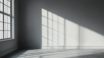 Empty gray room with natural light streaming through a window, creating shadows on the wall. Minimalist aesthetic and stark architectural lines. photo