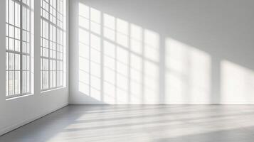 Sunlight streams through large windows, casting geometric patterns on the white walls and grey floor of an empty, spacious room. photo