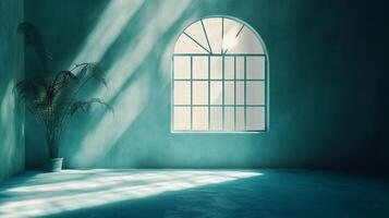 Sunlight streams into an empty teal room, illuminating a plant by a rounded window, casting light and shadow in a tranquil interior space. photo