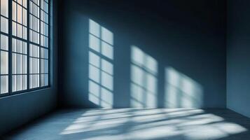 Sunlight streams through a large window illuminating an empty room. The shadows create interesting patterns on the wall and the floor. photo