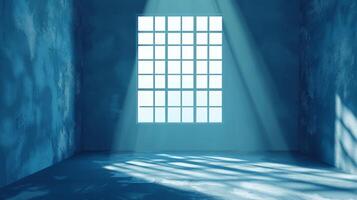 A blue room, with a large window letting in light. The floor and walls are concrete, casting a shadow of the window pattern in the room. photo