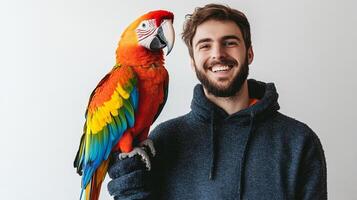 Portrait of a smiling man with a colorful macaw perched on his arm against a plain background, showcasing companionship and vibrant plumage. photo