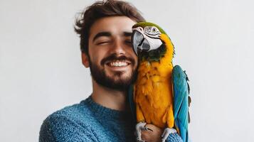 A smiling man joyfully embraces a vibrant parrot, their bond evident in this heartwarming display of animal companionship and affection. photo