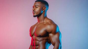 A muscular African-American man showcases his toned physique against a backdrop illuminated with vibrant red and blue hues, showing strength. photo