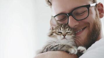 Happy man embraces a fluffy tabby kitten, eyes closed, smile evident in a heartwarming display of affection and feline companionship. photo