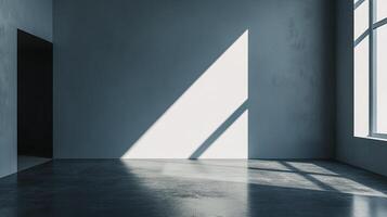 Sunlight streams through a window, casting angular shadows on a grey wall and floor in an otherwise empty room, creating a minimalist aesthetic. photo