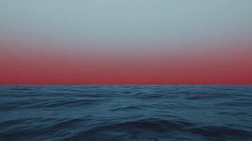 Serene seascape at dusk, featuring tranquil blue water gently rippling under a gradient sky shifting from red to soft blue, a peaceful horizon. photo