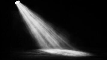 A dramatic spotlight beam illuminates a darkened stage or space, creating a focused point of interest and theatrical atmosphere. photo