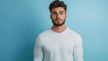 Portrait of a handsome man in a white long-sleeved shirt against a bright blue background, looking directly at the camera with a serious expression. photo