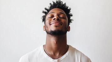 A handsome man with closed eyes appears to be feeling peaceful and at ease, with a serene expression of joy against a plain background. photo