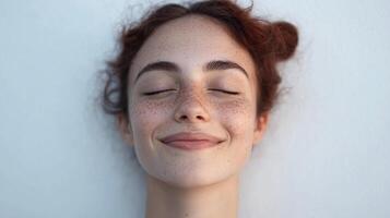 Content woman smiling, with eyes closed. Expressing joy and calm, enjoying peace. Prominent freckles adding character to her youthful face. photo