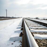 Snow covered railway tracks stretching towards the horizon, with a white background and electric poles lining the route photo