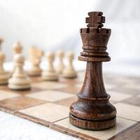Wooden chess king piece in sharp focus on a chessboard, with out of focus pawns and pieces behind it, showcasing fine craftsmanship photo