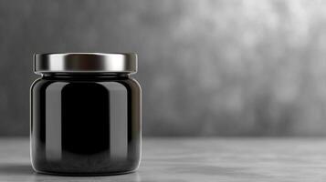 Black glass jar on a grey surface with subtle background texture photo