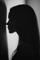 Silhouette of a woman leaning against a wall in soft light photo