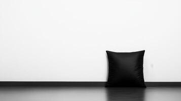 Soft black pillow resting on a minimalist floor against white wall photo