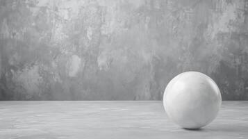 White sphere rests on textured gray surface in minimal setting photo